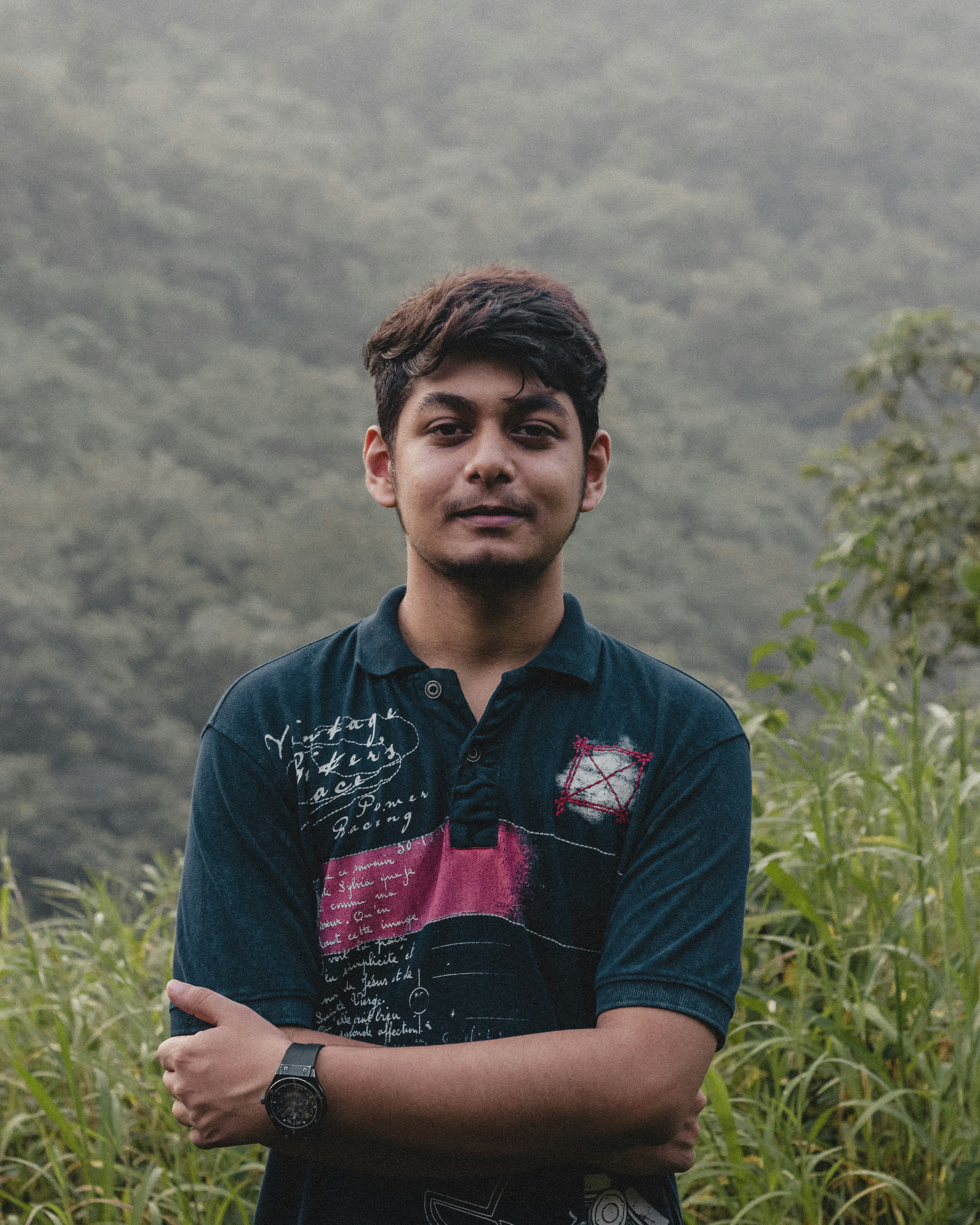 a man standing in front of a lush green hillside